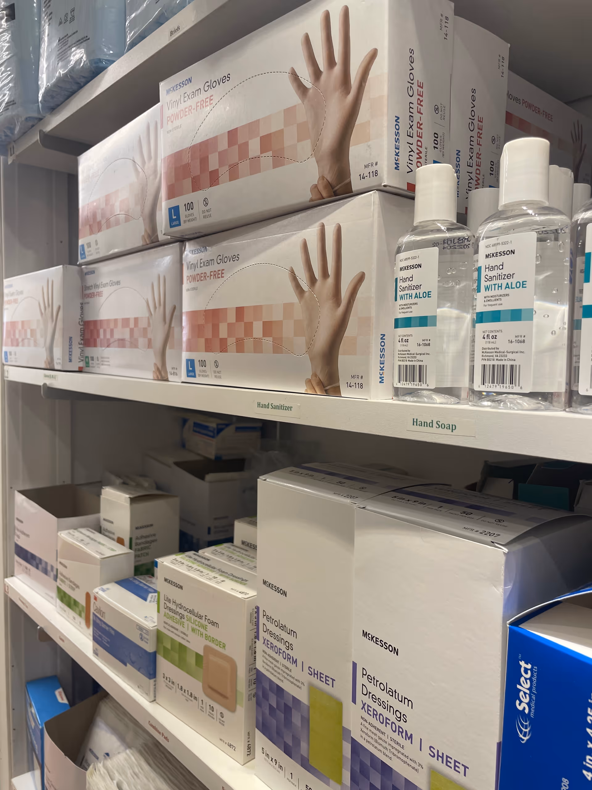 Shelves filled with gloves, sanitizers, and medical supplies in a facility storage area.