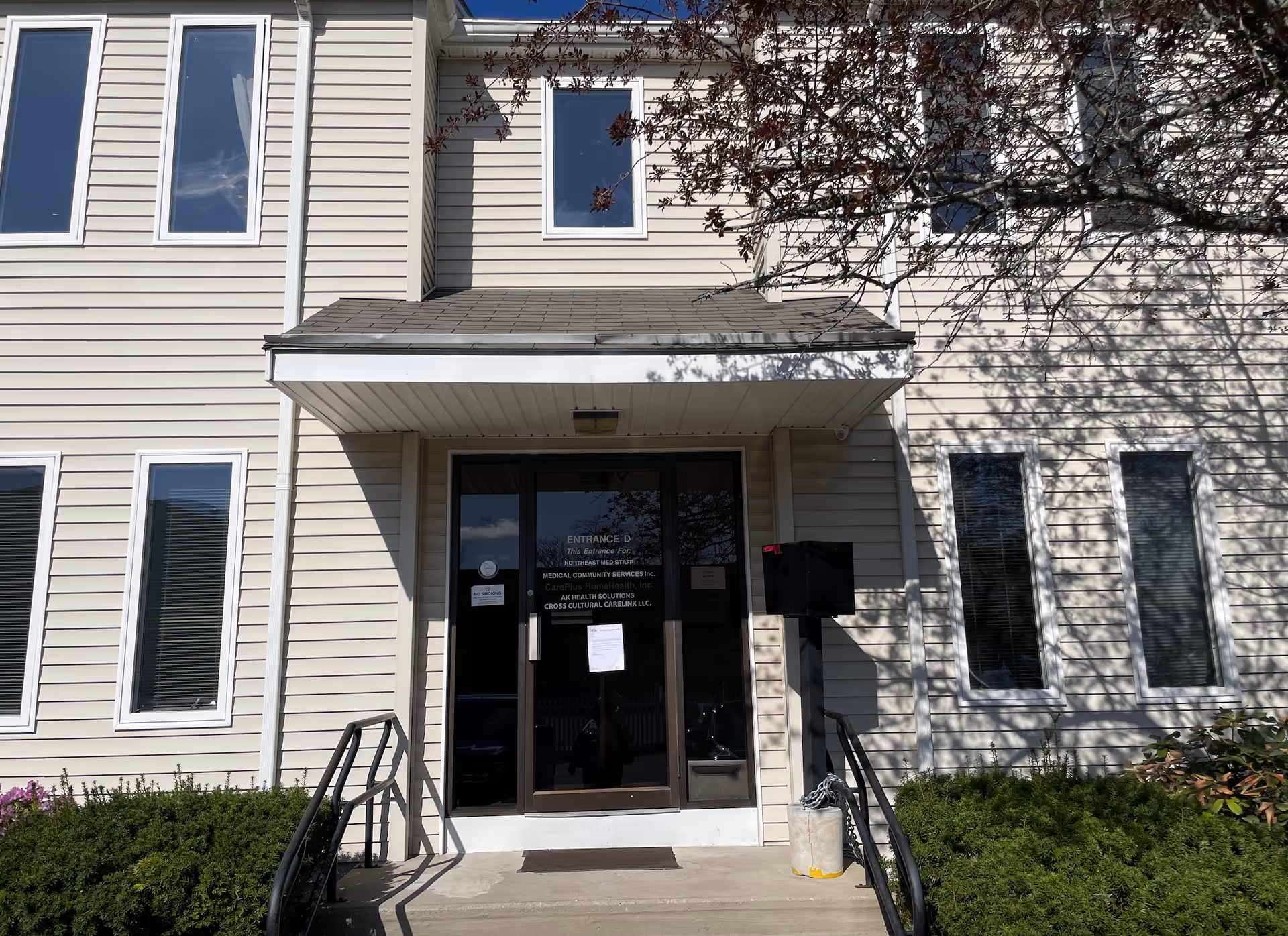 Front entrance of a beige multi-story senior living building with glass doors.