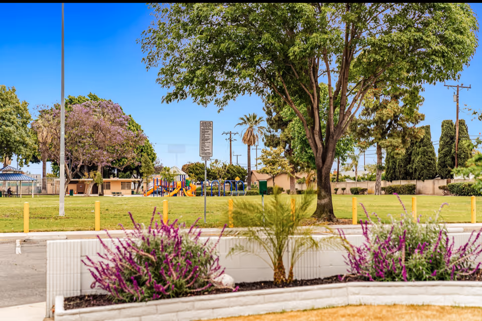 Sunny outdoor park area on a senior living campus with a colorful playground.