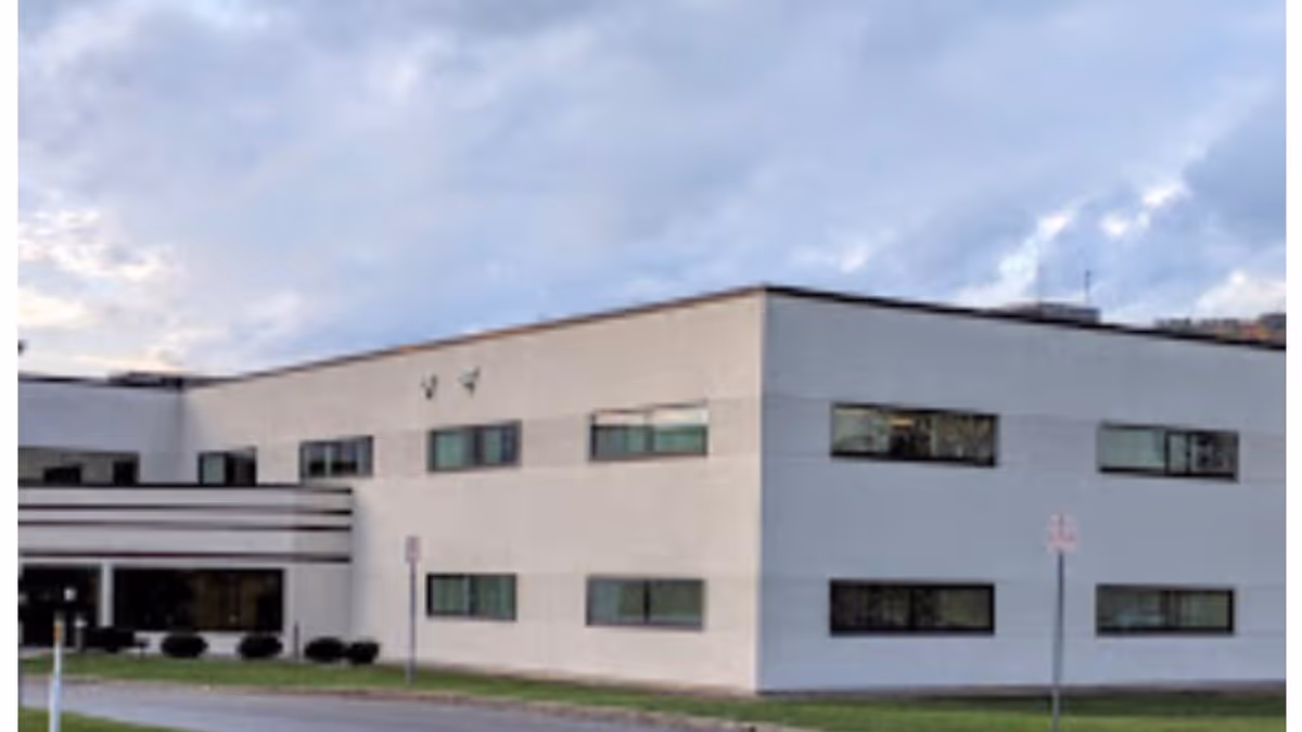 White modern medical facility exterior with rectangular windows under a cloudy sky.