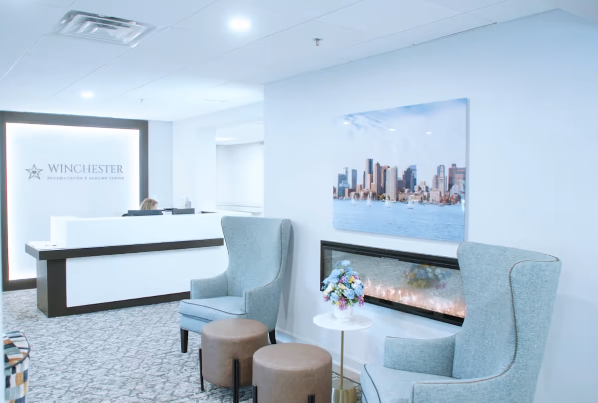 Reception area with white desk, teal chairs, fireplace, and Winchester signage.