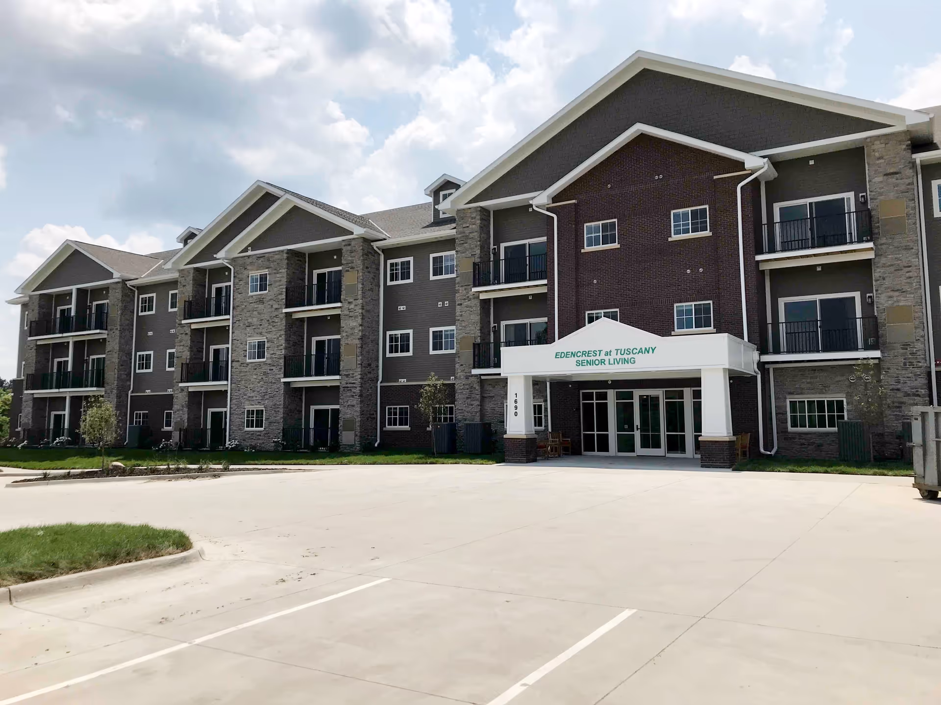 Front exterior of a three-story senior living building with balconies and a covered entrance reading 'Edencrest at Tuscany Senior Living'.