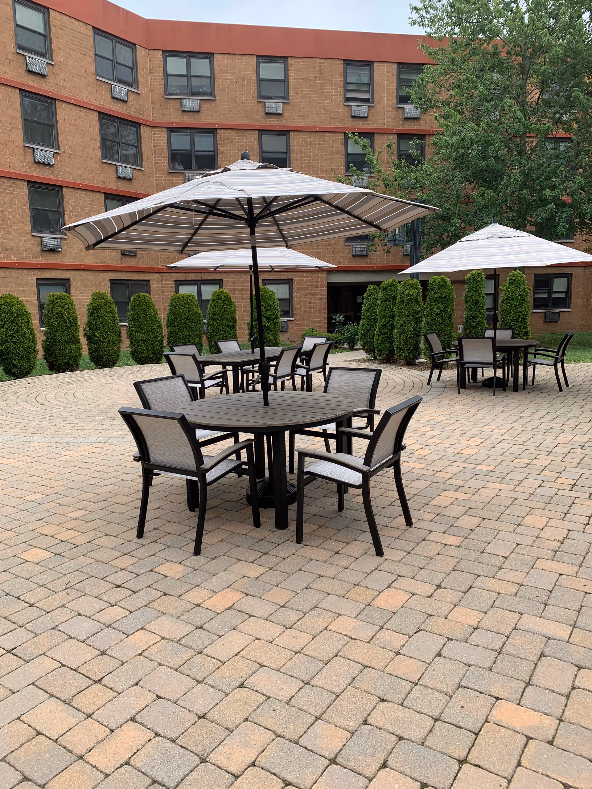 Outdoor courtyard of Evergreen Manor with shaded tables and patio seating.