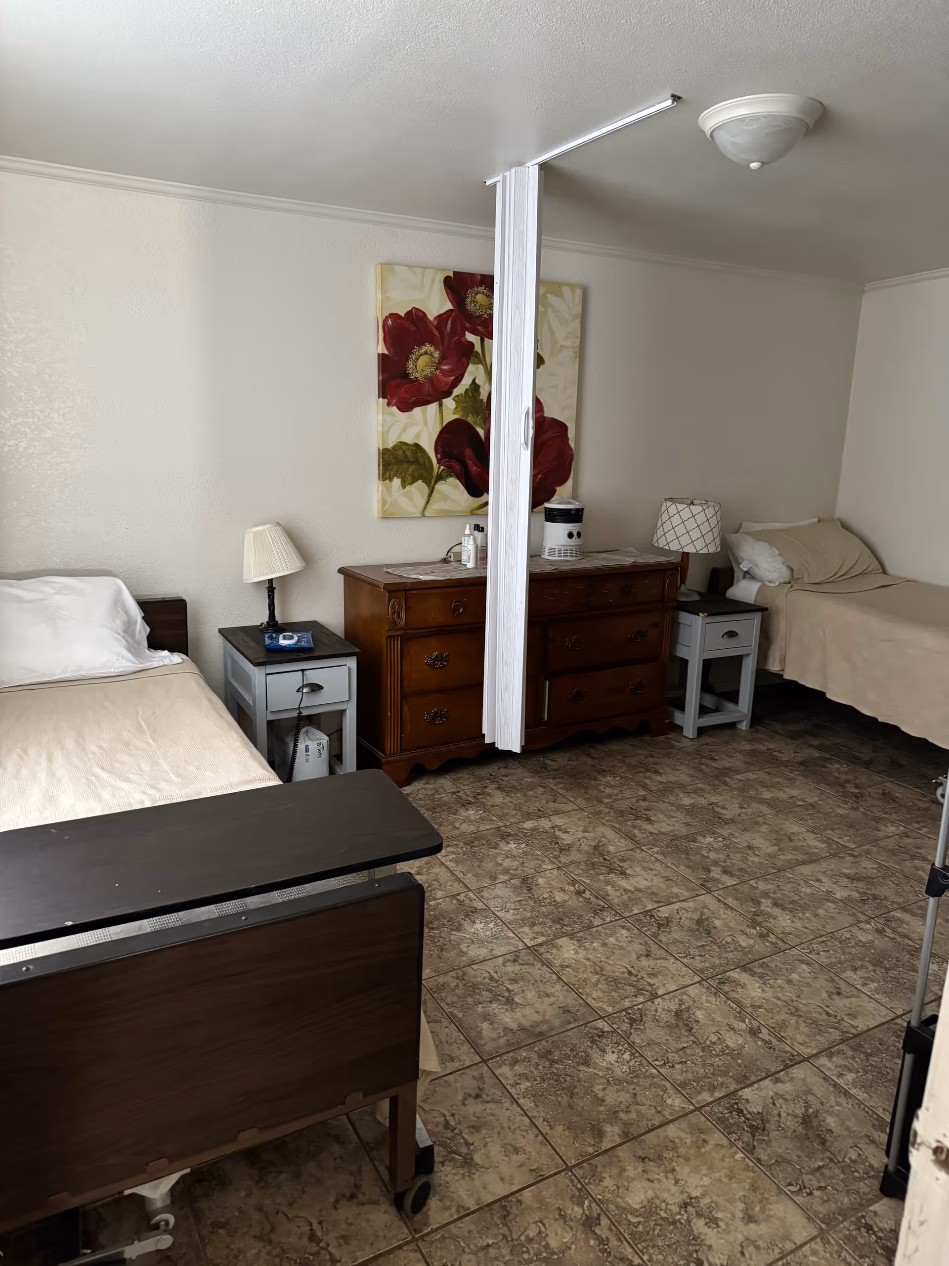 Shared bedroom with two single beds, nightstands, a dresser, and a ceiling-mounted privacy divider.