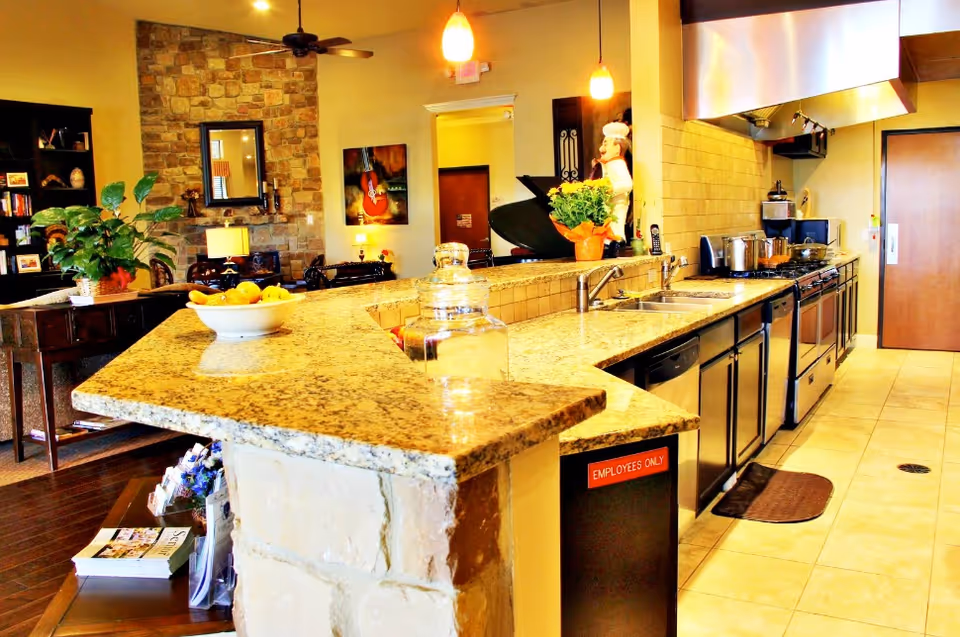 A modern kitchen with granite island, stainless appliances, and an employees-only cabinet.