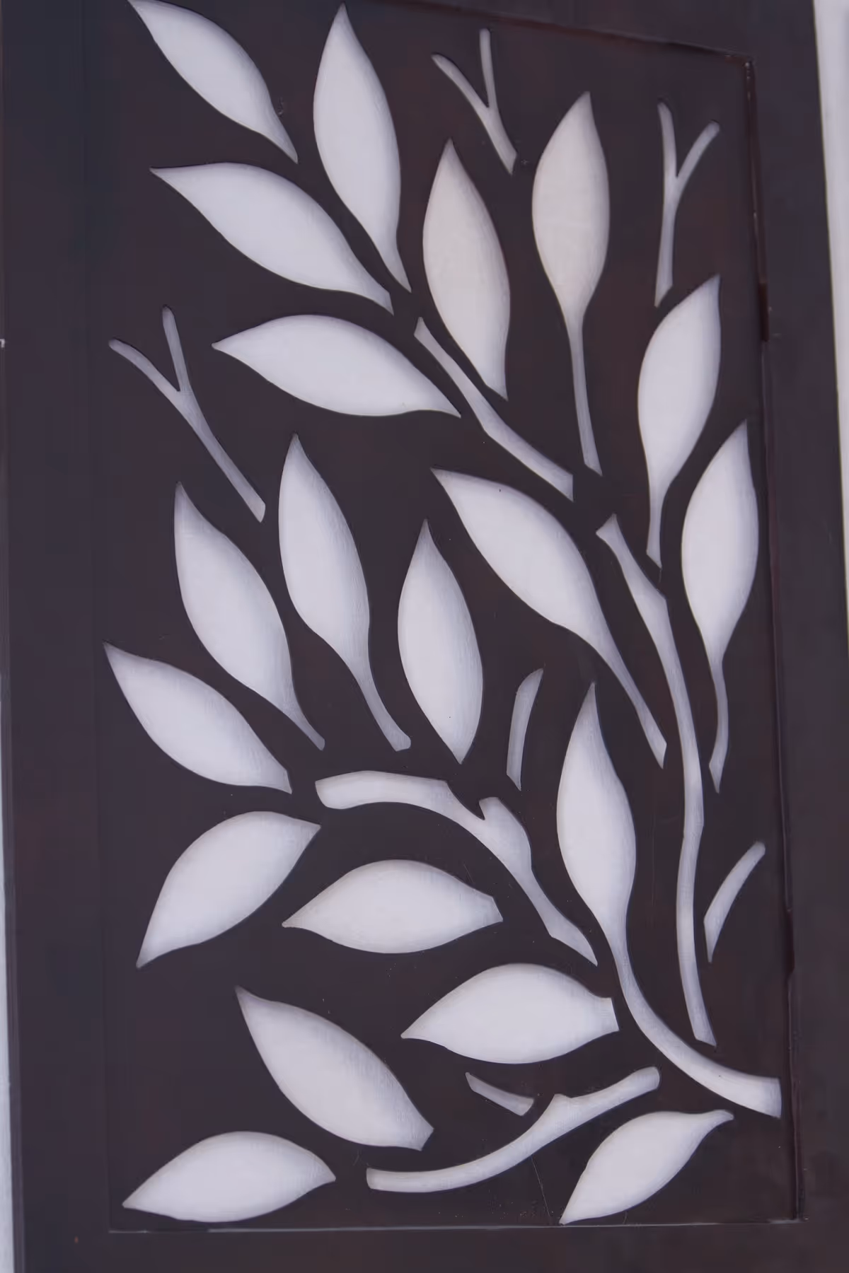 Close-up of a dark door panel with a white leaf motif.