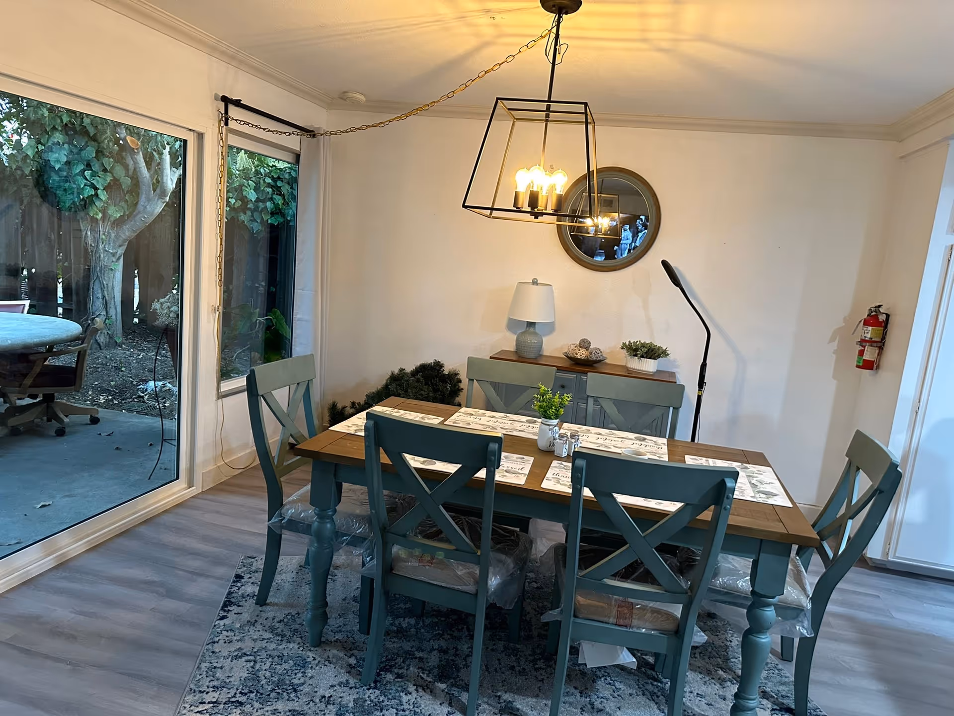 A dining room with a wooden table, teal chairs, and pendant light.