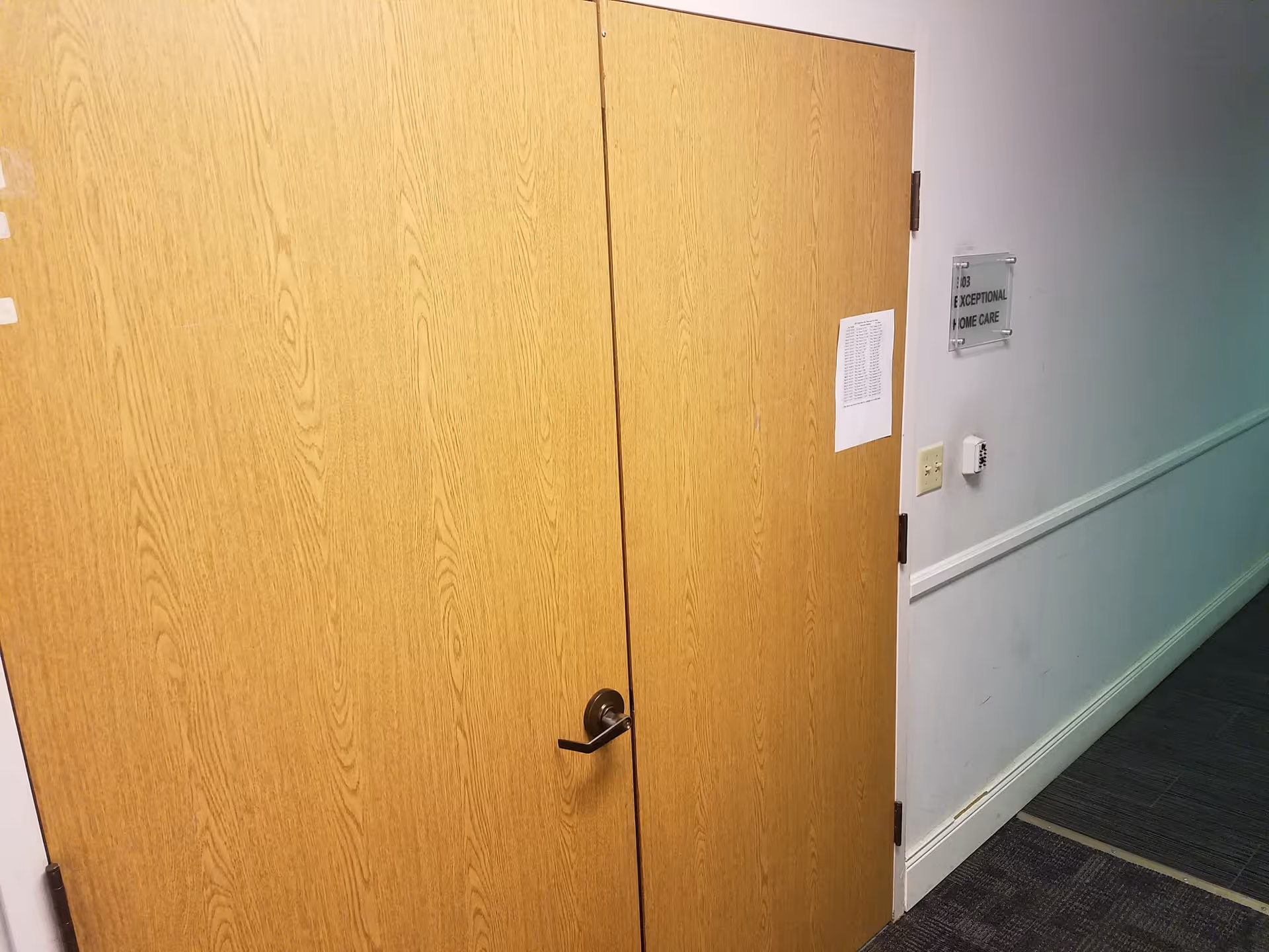 Corridor with tall wooden doors and a wall sign in a senior care facility.