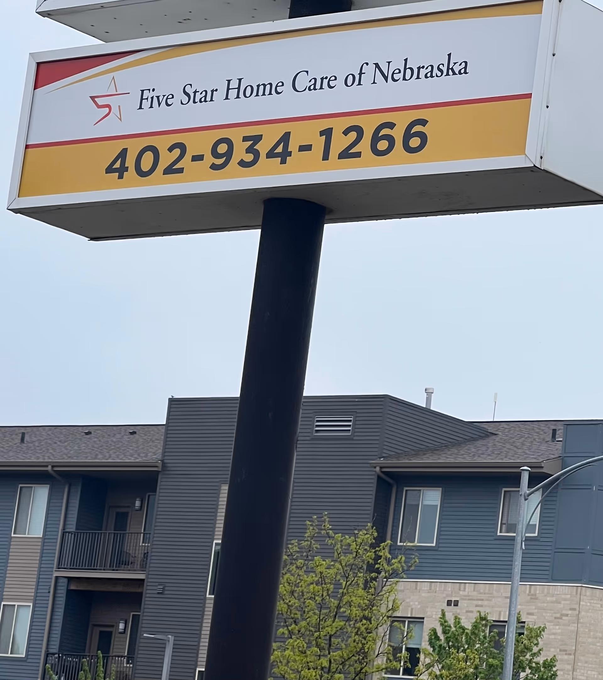 Outdoor sign displays Five Star Home Care of Nebraska and phone number in front of building.