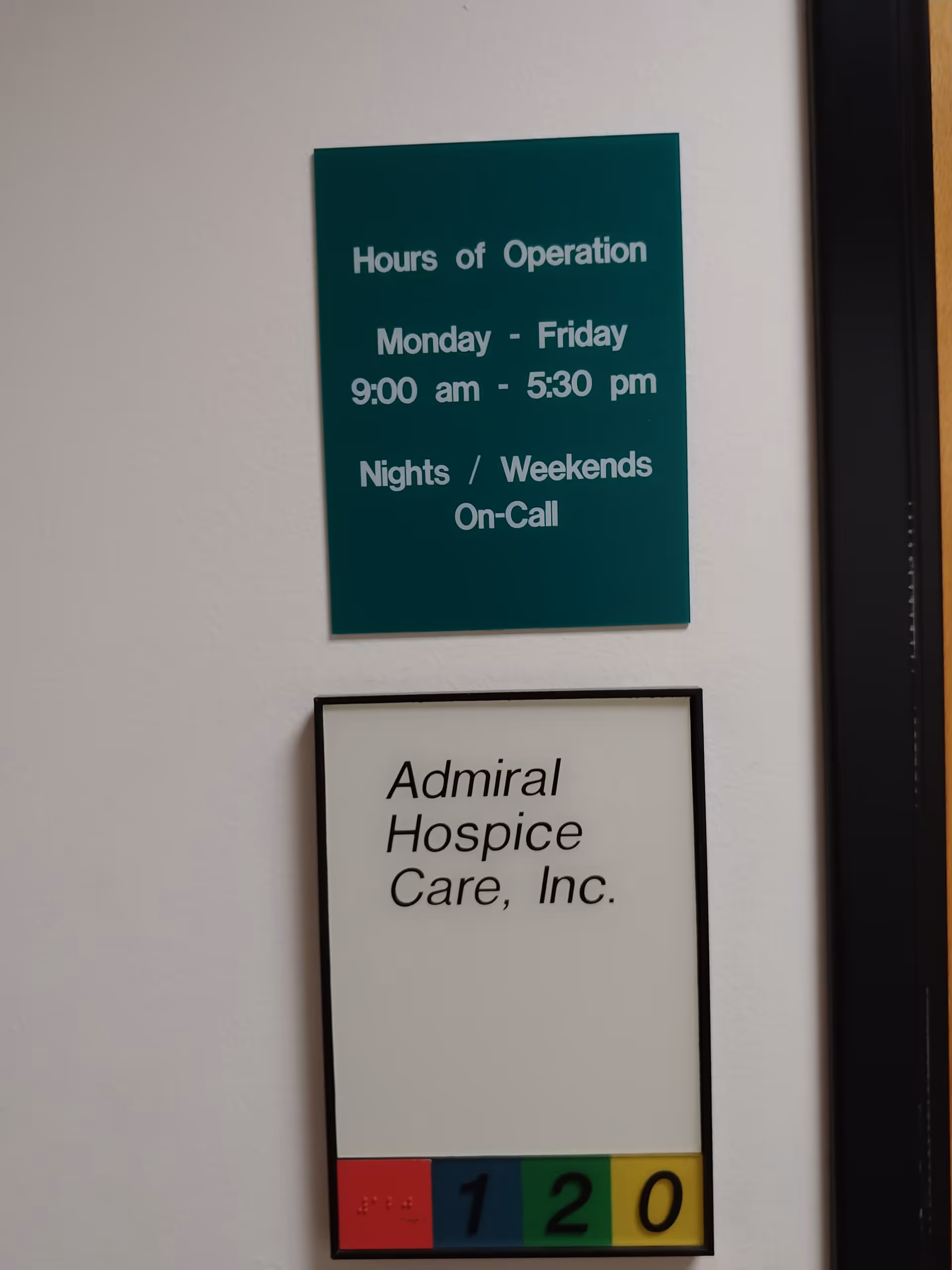 Teal hours-of-operation sign and white Admiral Hospice Care, Inc. sign on a wall.