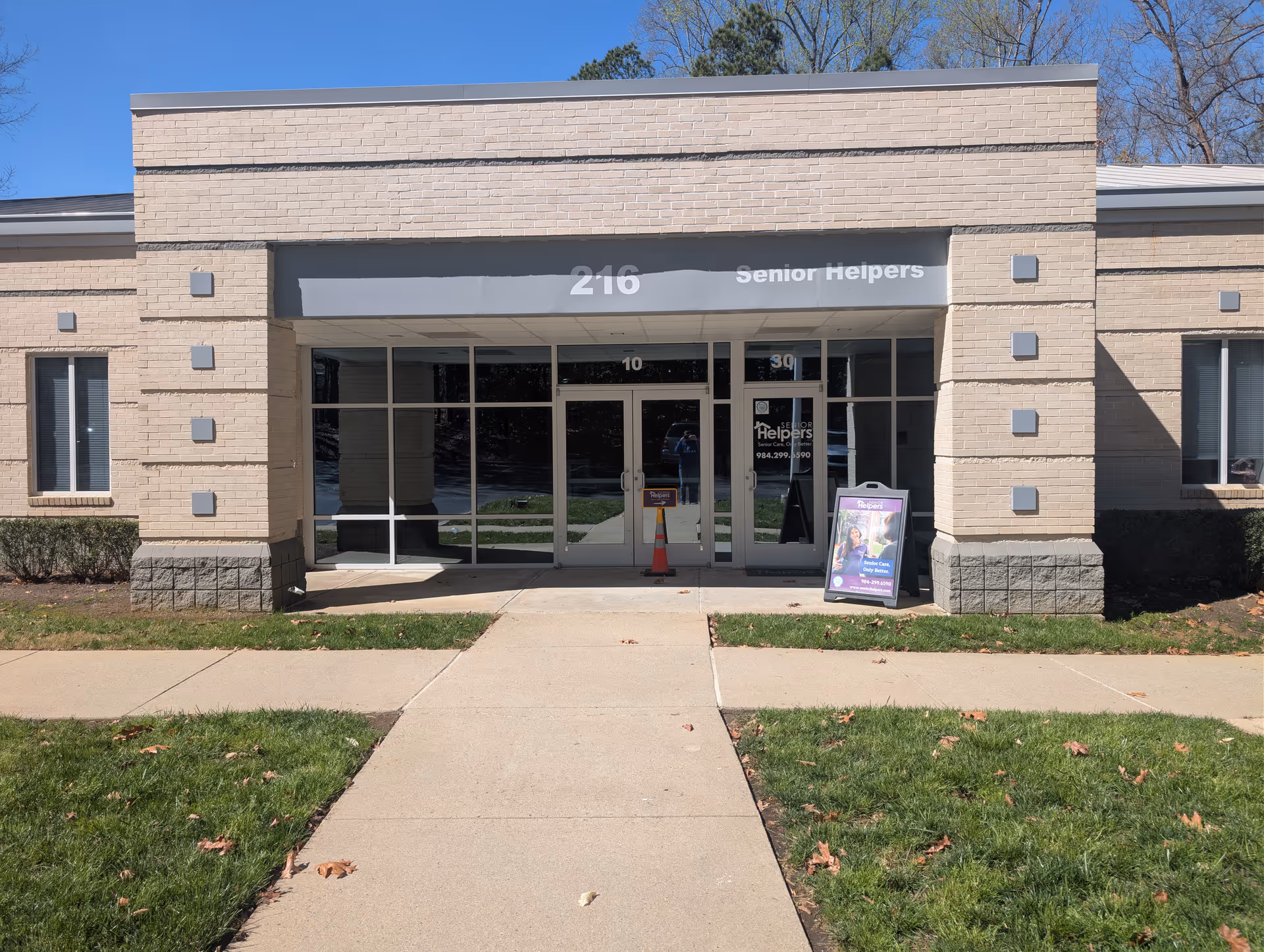 Front view of a Senior Helpers facility entrance with glass doors and a sidewalk.