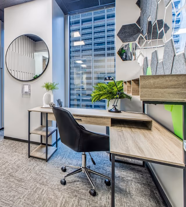 Modern office desk area with chair, lamp, plants, a mirror, and hexagonal wall panels.