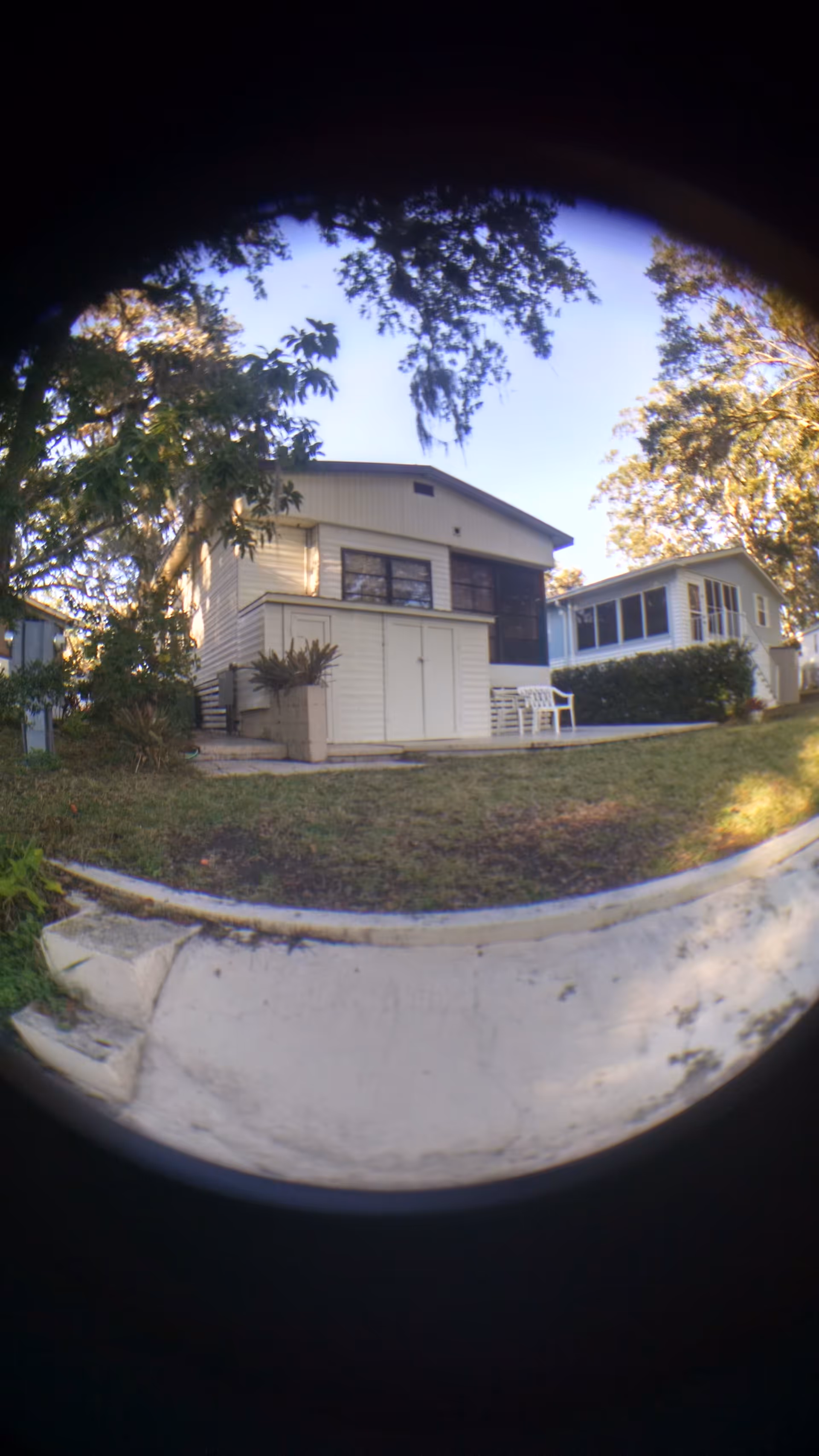 Front exterior of a Sugar Creek Estates building with lawn, trees, and a small patio.