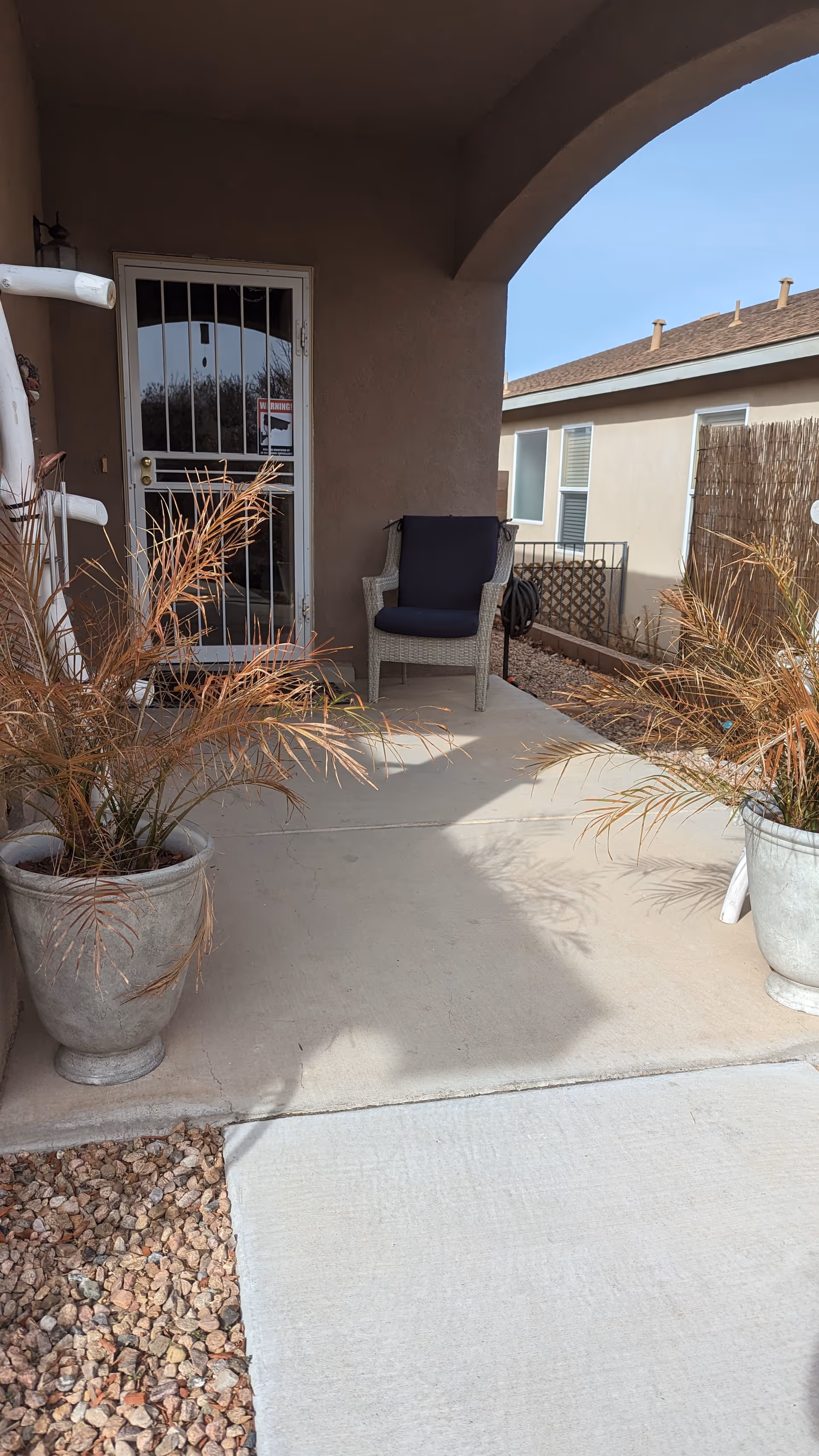 Front porch with chair, potted plants, and doorway to Desert Hills Assisted Living Facility.
