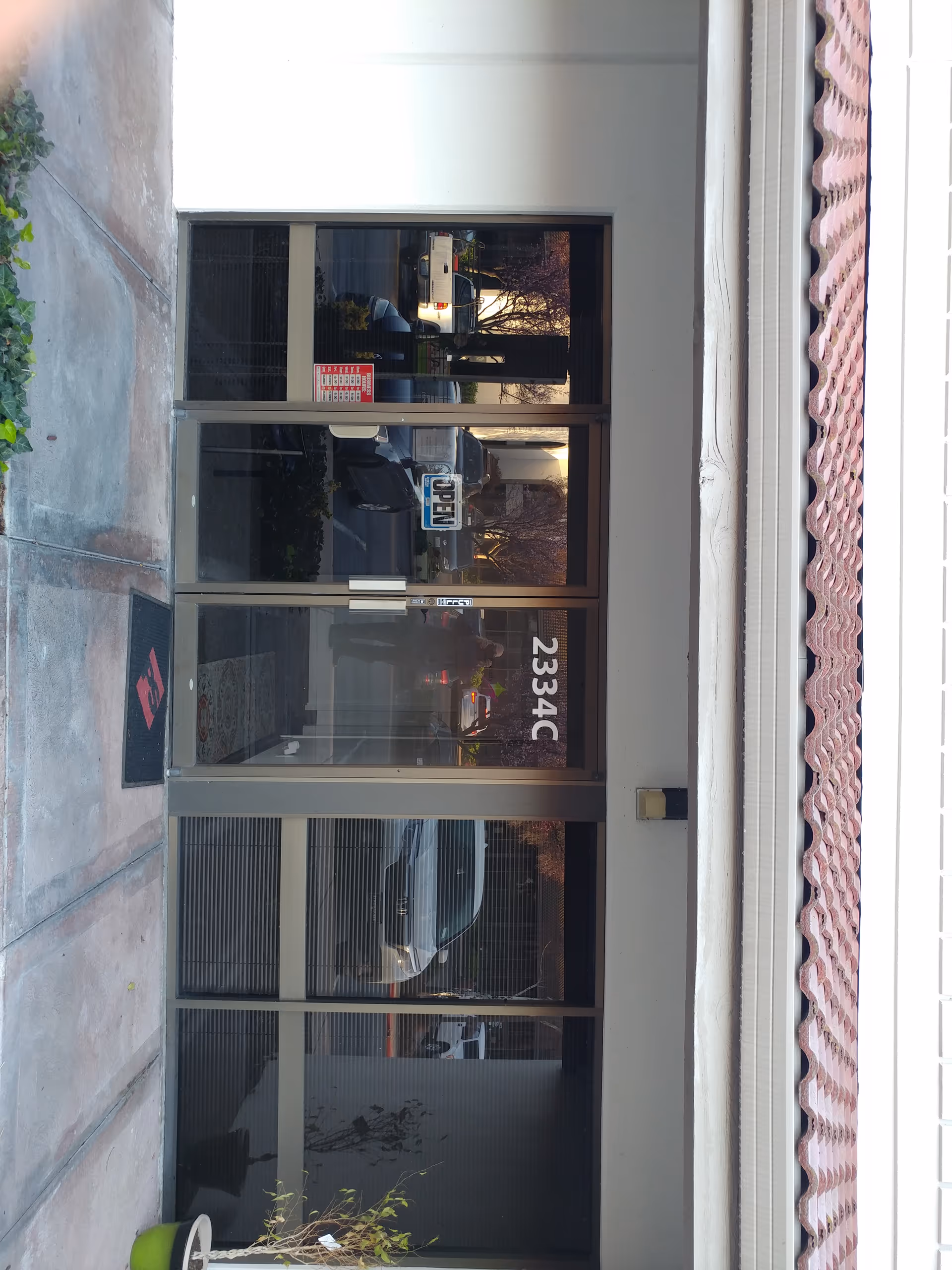 Front entrance of a building with glass doors and sidewalk reflections.