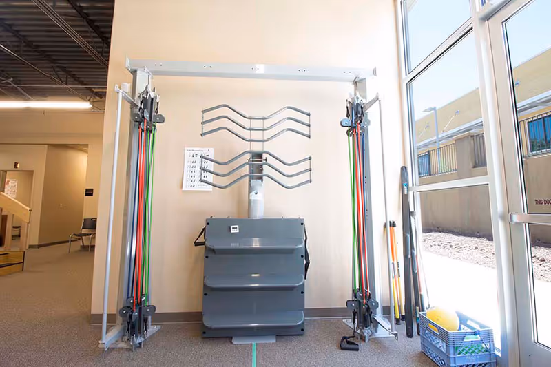 Fitness equipment rack and cable resistance machines inside a senior living facility gym.