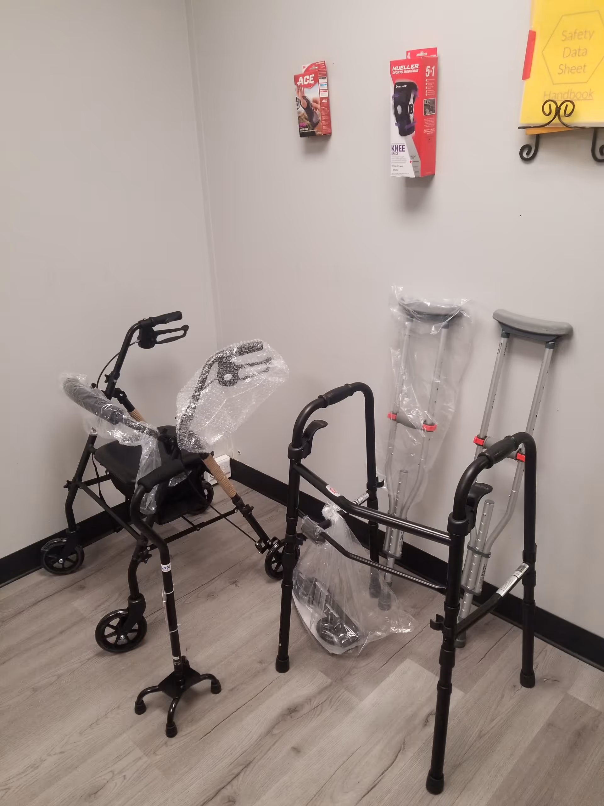 Corner of a facility room showing wrapped walkers and crutches leaning against walls.