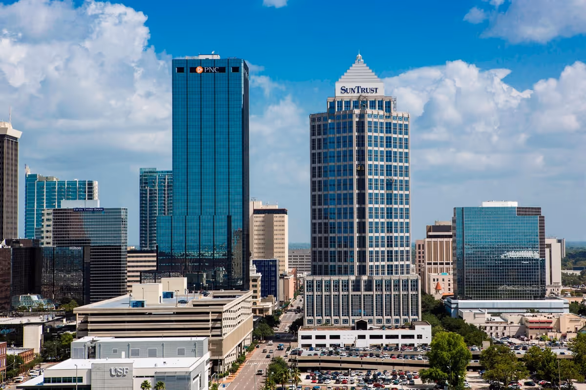 A downtown city skyline with glass skyscrapers against a blue sky.