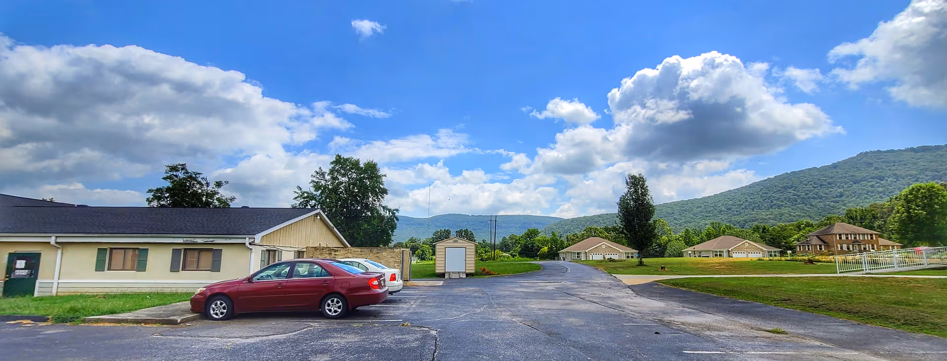 Exterior view of Woodhaven Personal Care campus with parking lot and distant hills