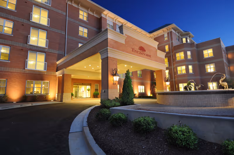 Exterior view of Trezevant senior living facility entrance with lit windows and landscaped driveway.