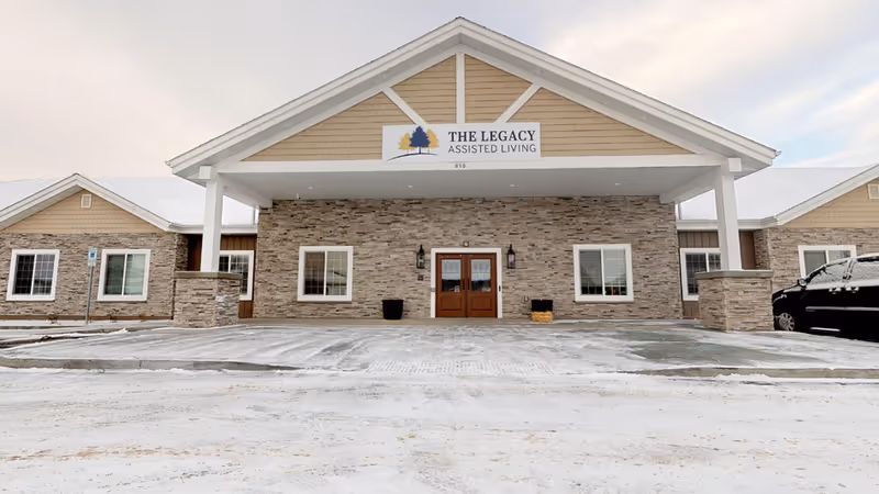Front view of The Legacy Assisted Living in the Heights, showing entrance and stone facade.