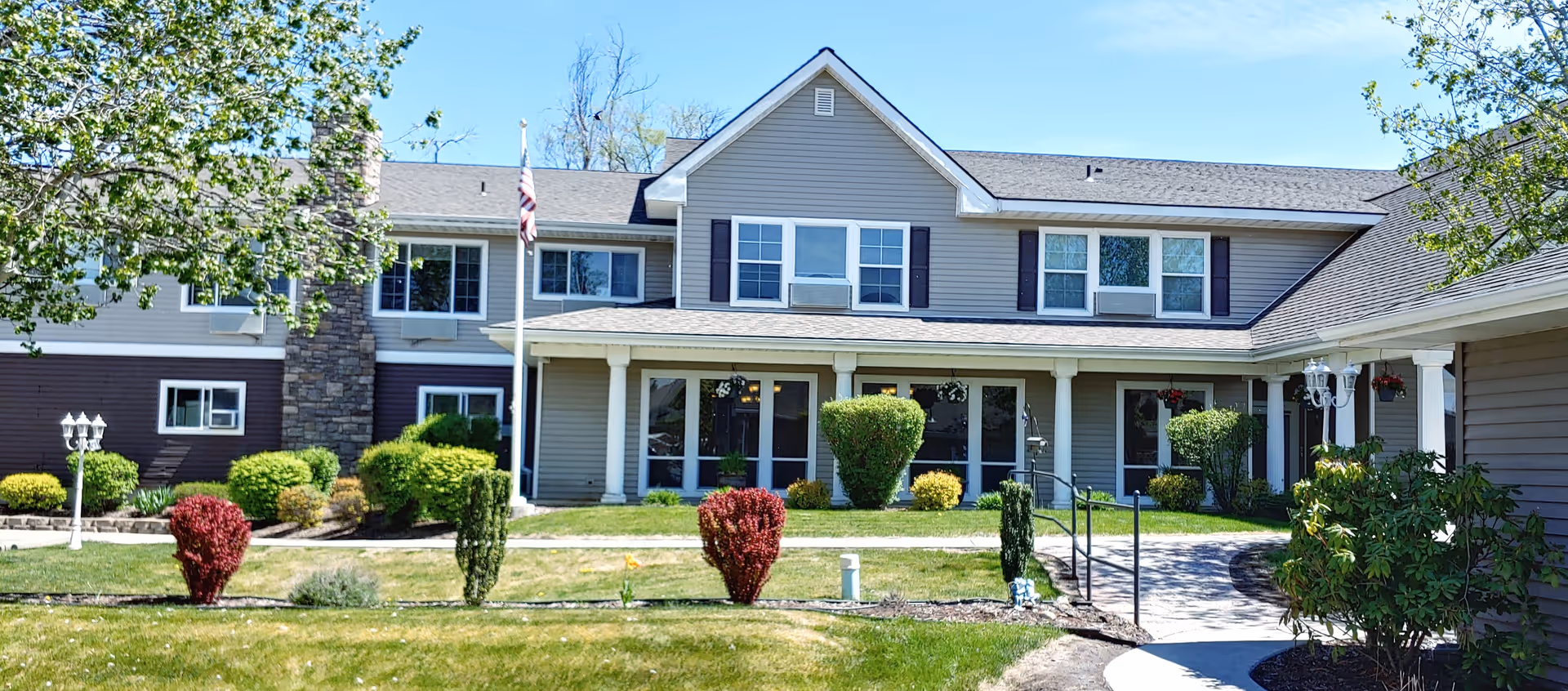 Two-story assisted living facility with manicured lawn and shrubs at the front entrance.