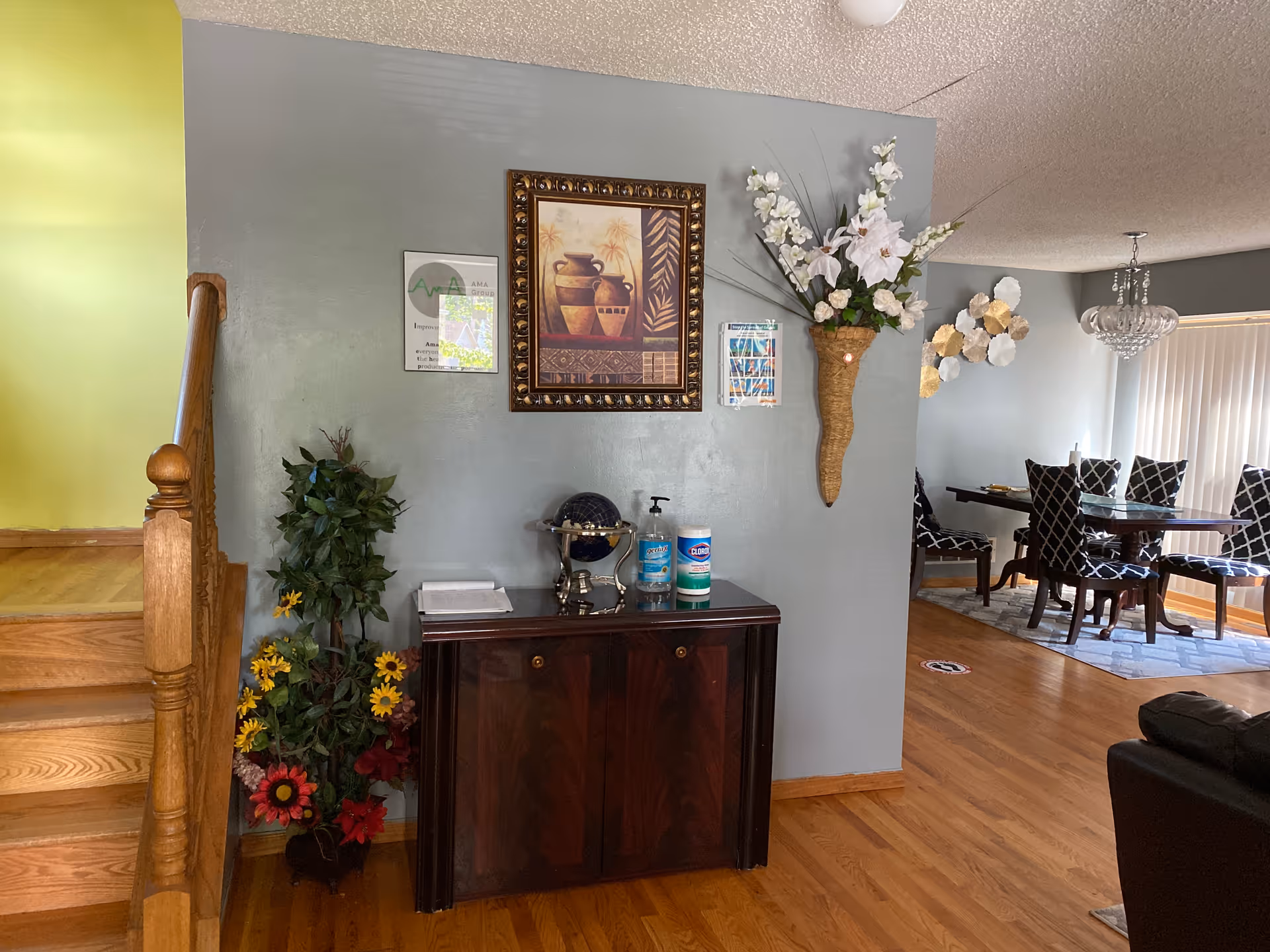 Interior common area with a console table, wall art, plants, and a dining space in back.