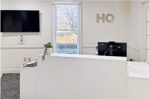 Reception desk in a bright facility lobby with a computer monitor and HQ letters