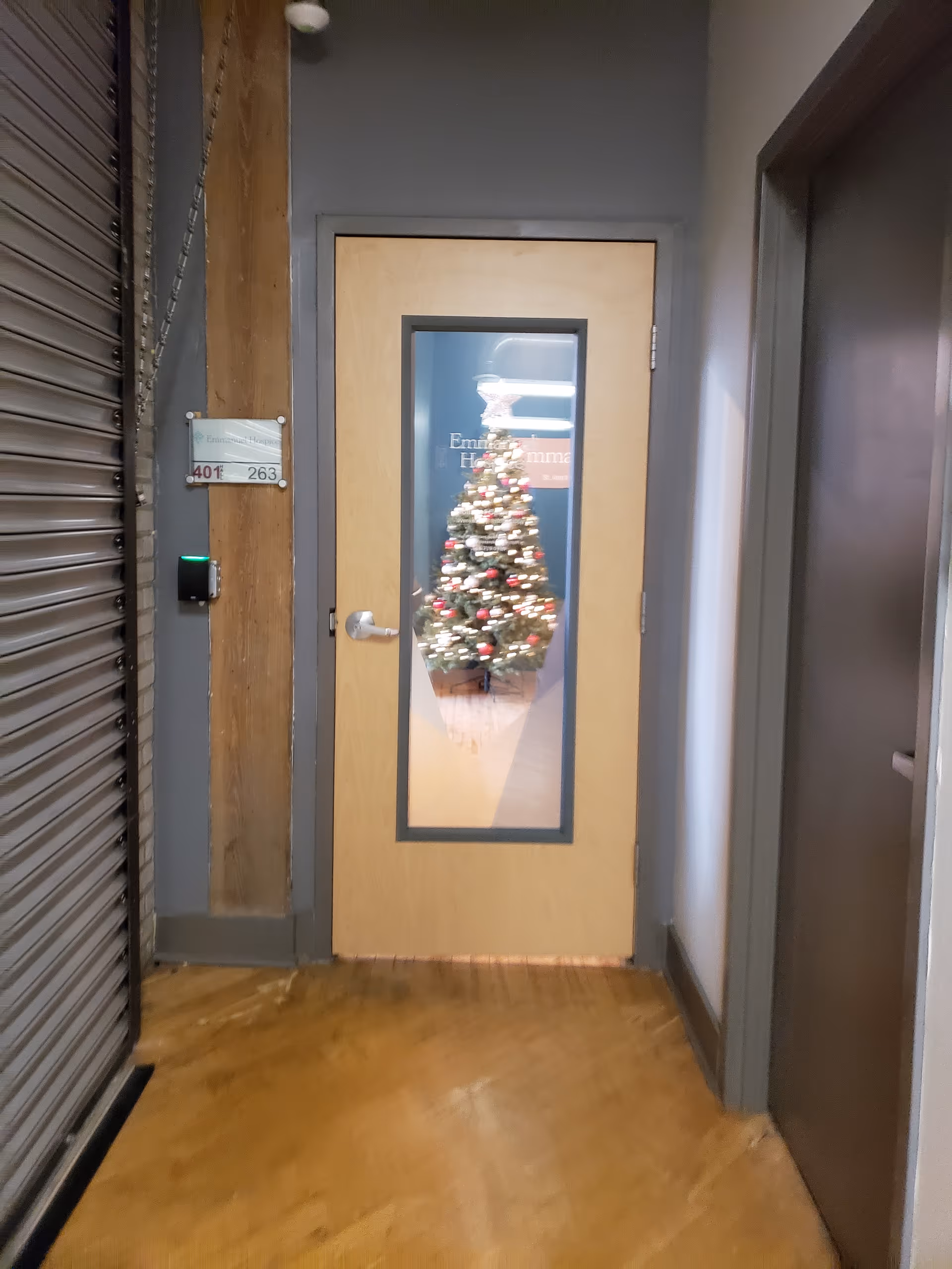 Interior hallway with a door window displaying a lit Christmas tree.