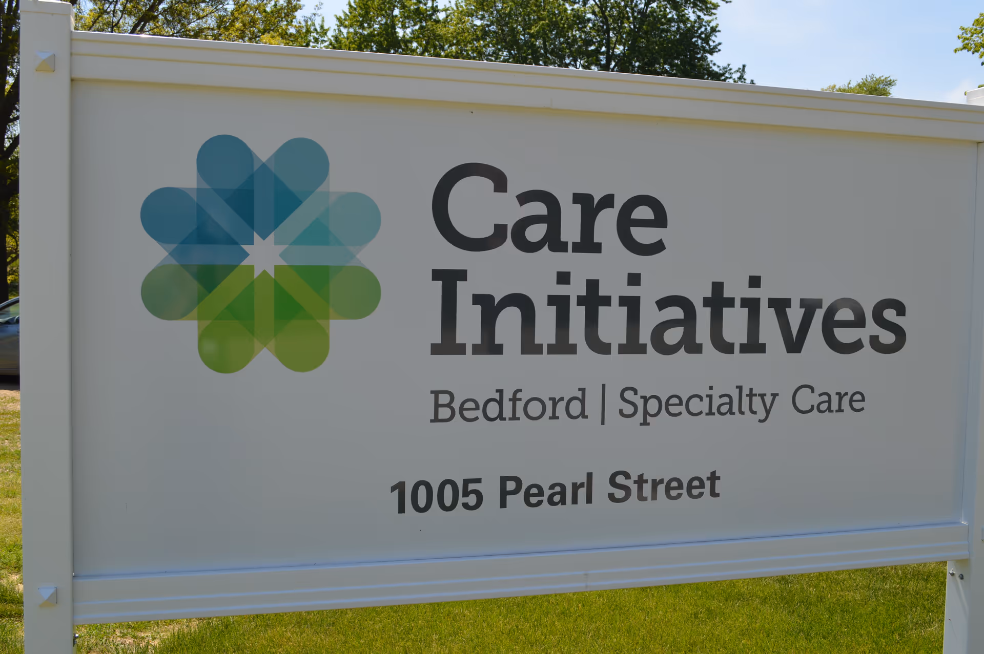 Outdoor sign for Care Initiatives Bedford Specialty Care located at 1005 Pearl Street, with a colorful geometric logo on the left side of the sign.