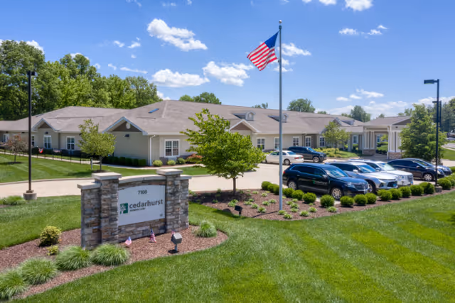 Front exterior of Addington Place of Edwardsville, showing a flagpole, sign, and parked cars.
