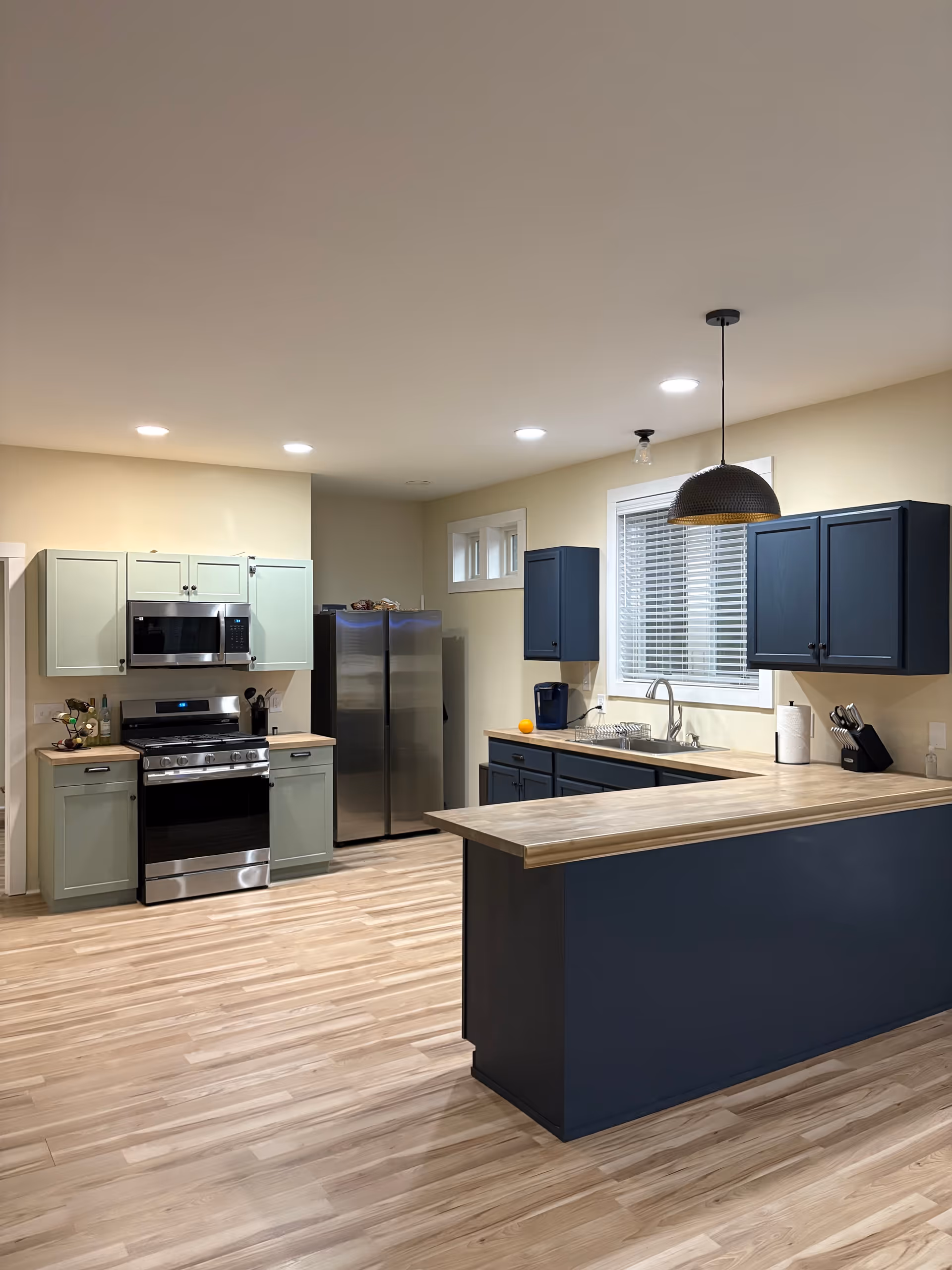 Modern kitchen with blue cabinets, stainless appliances, and a wooden island.