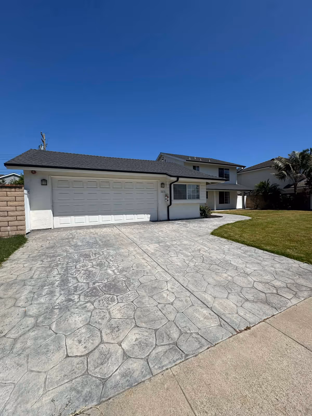 Front view of a residential facility with a two-car garage and stamped driveway.