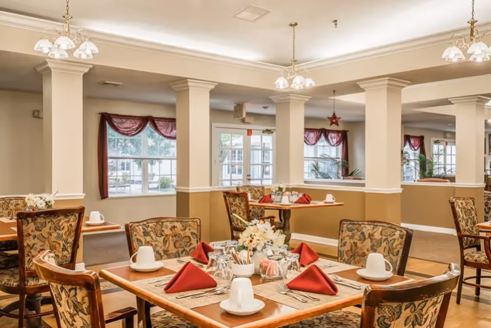 Interior dining room with round tables, floral centerpieces, and red napkins.