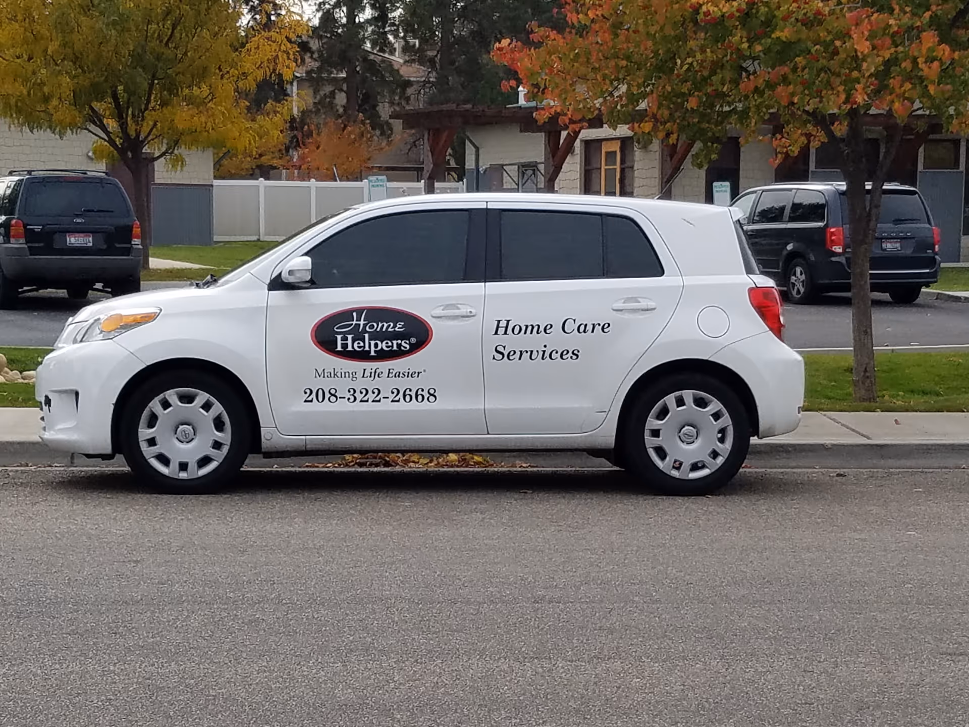 White van with Home Helpers branding and phone number parked along a street.