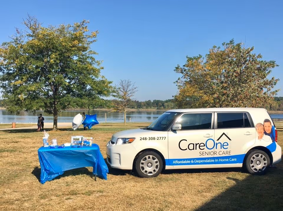 CareOne Senior Care promotional van beside a blue-table display by a lake.