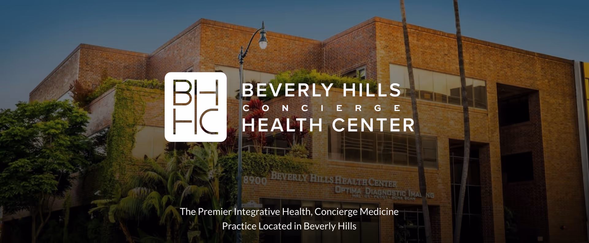 Exterior view of Beverly Hills Concierge Health Center building with large logo overlay
