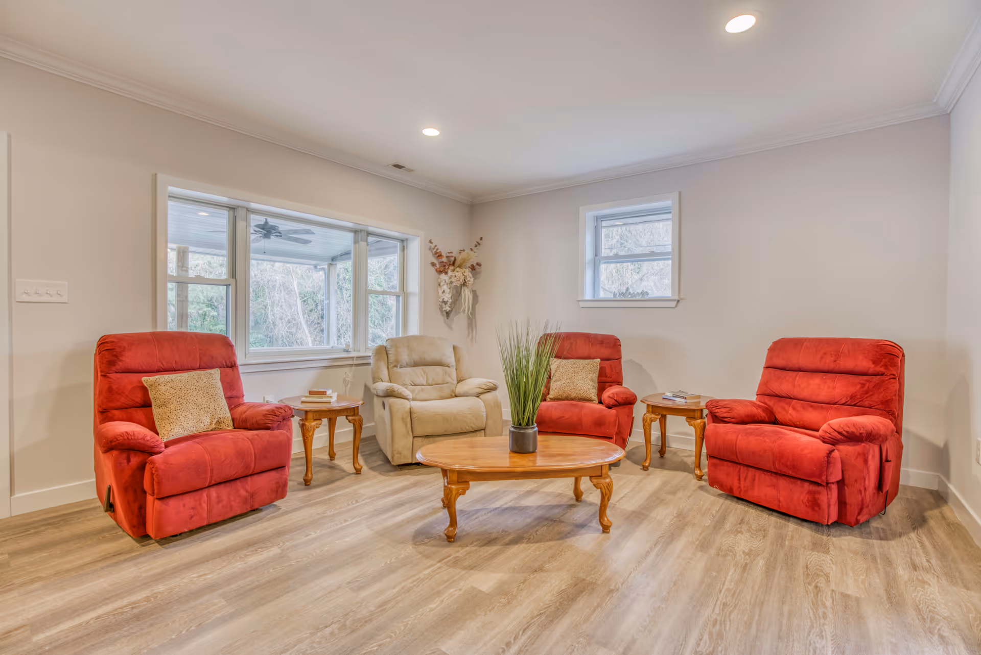 Lounge area in a senior living facility with red recliners around a wooden coffee table.