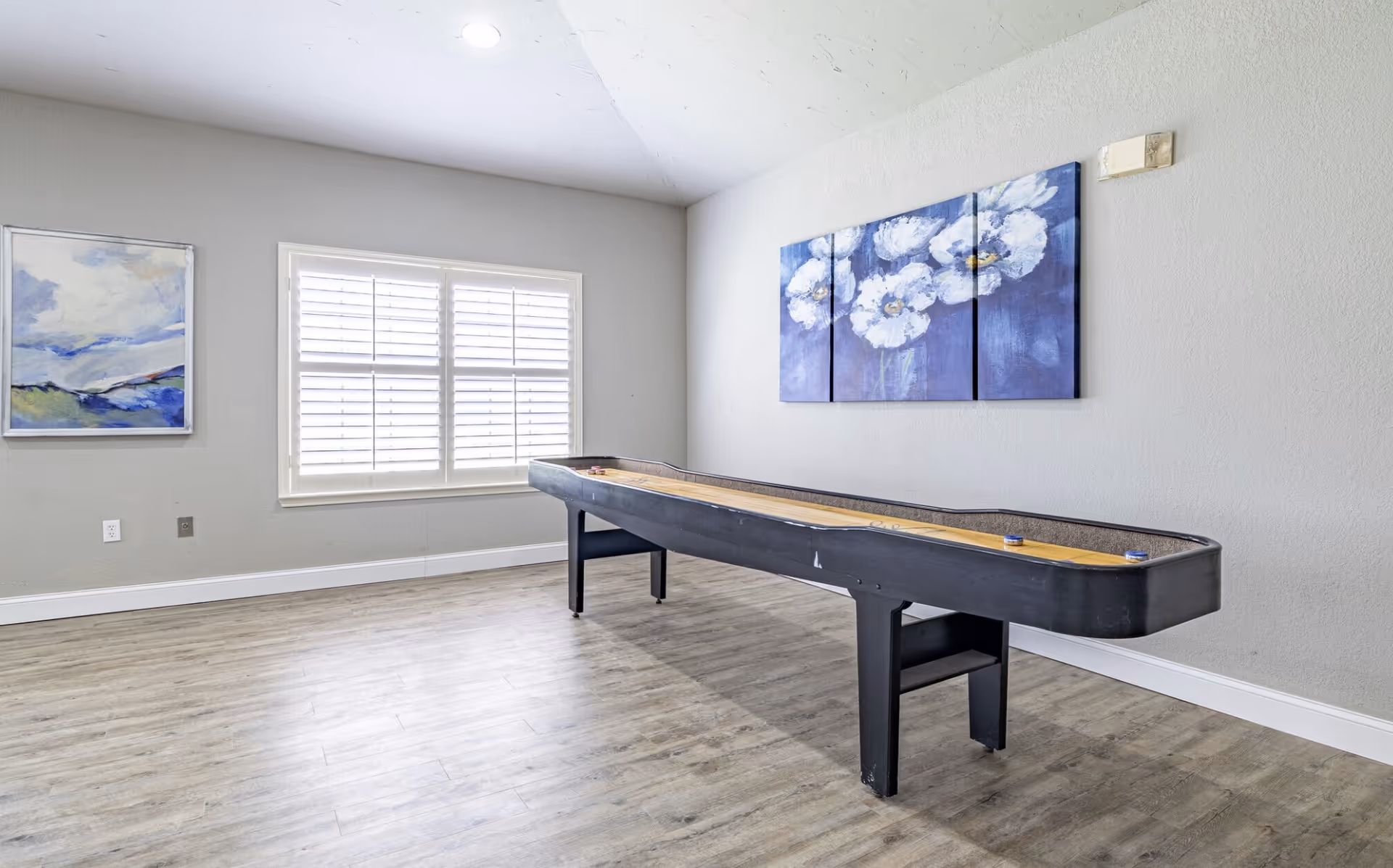 Interior recreation room with a pool table, windows, and wall art.