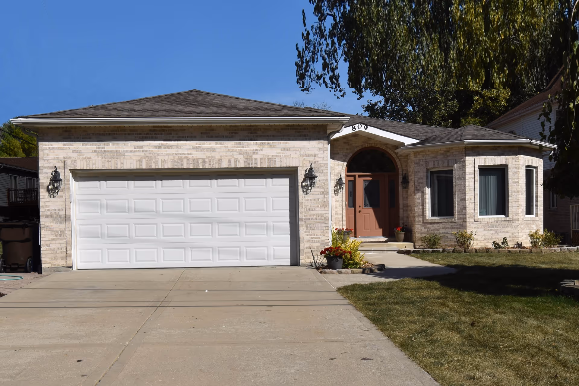 Front exterior of a single-story brick house with a two-car garage, driveway, and front entrance.
