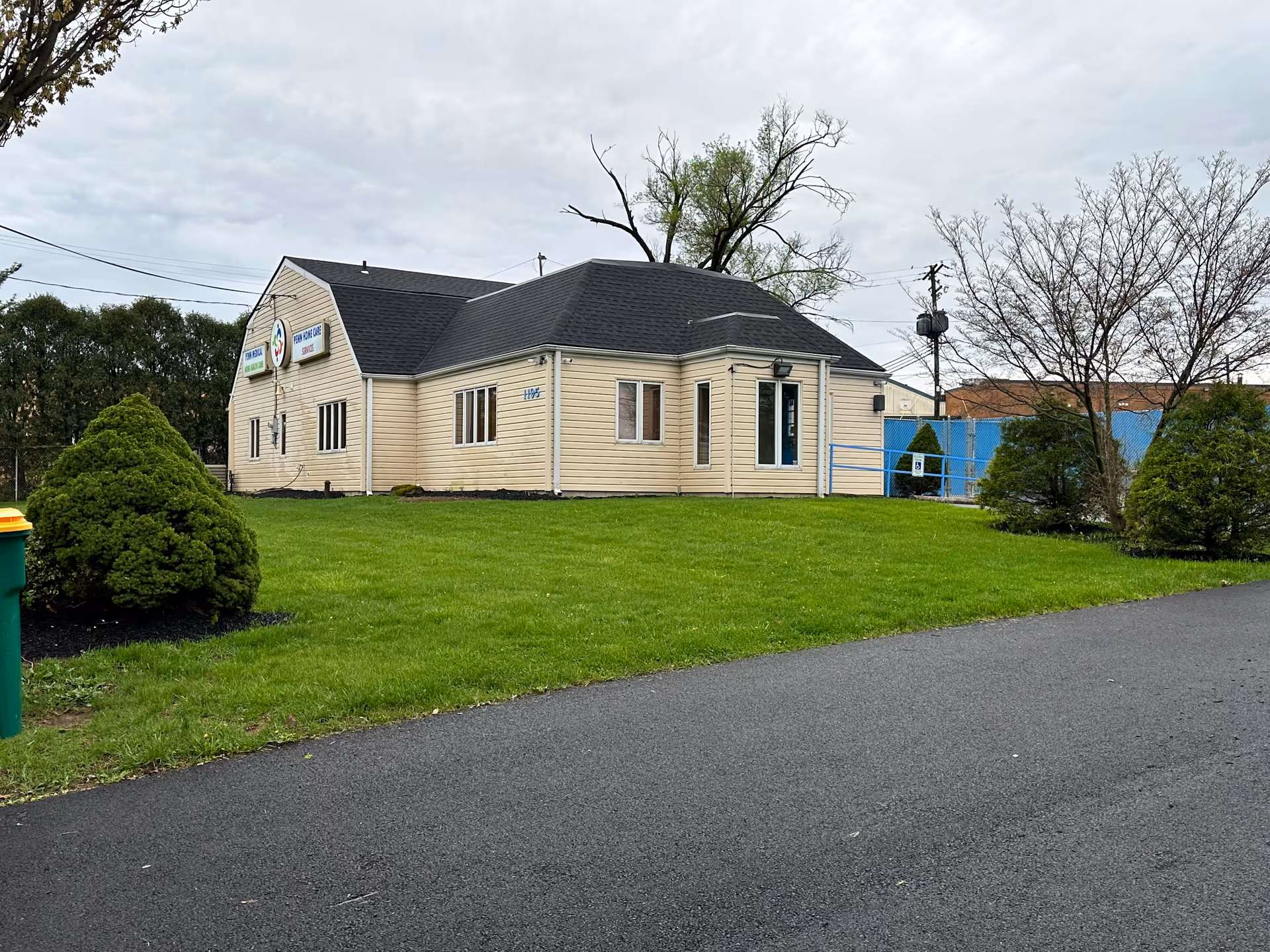 Exterior view of a beige senior care building with green lawn and paved road.