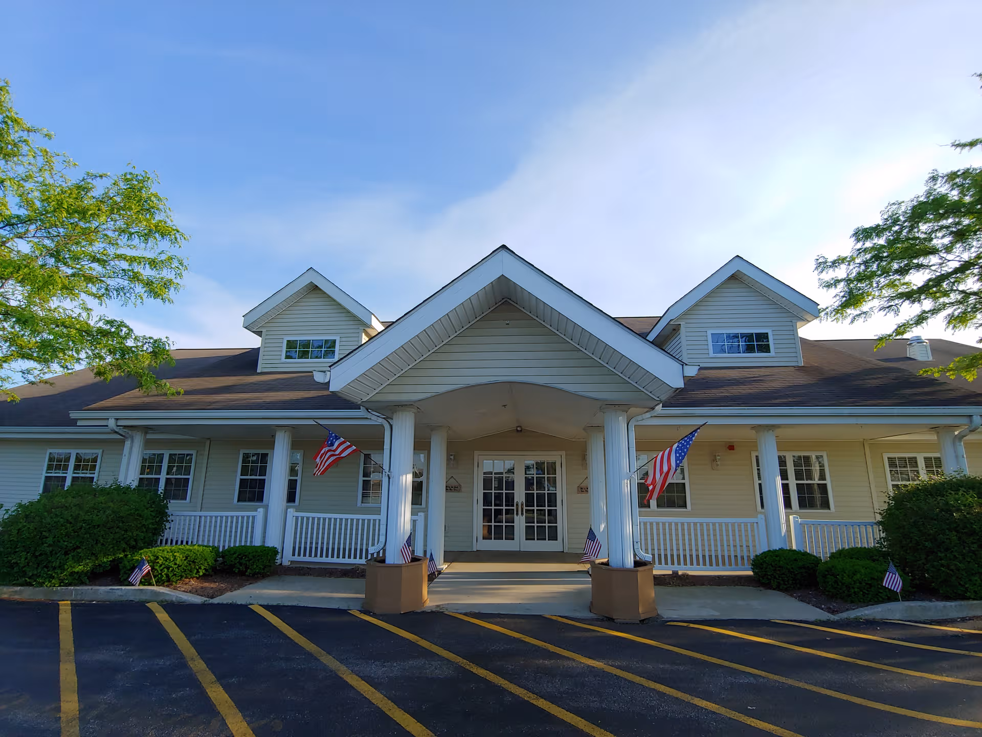 Front view of Trustwell Living at Settlers Place entrance with flags and columns.