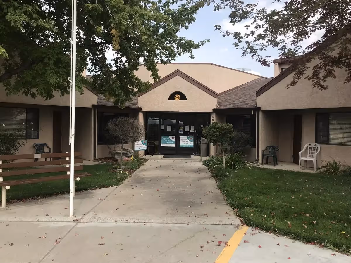 Front entrance of Madison House-Assisted Living with a walkway, benches, and greenery.