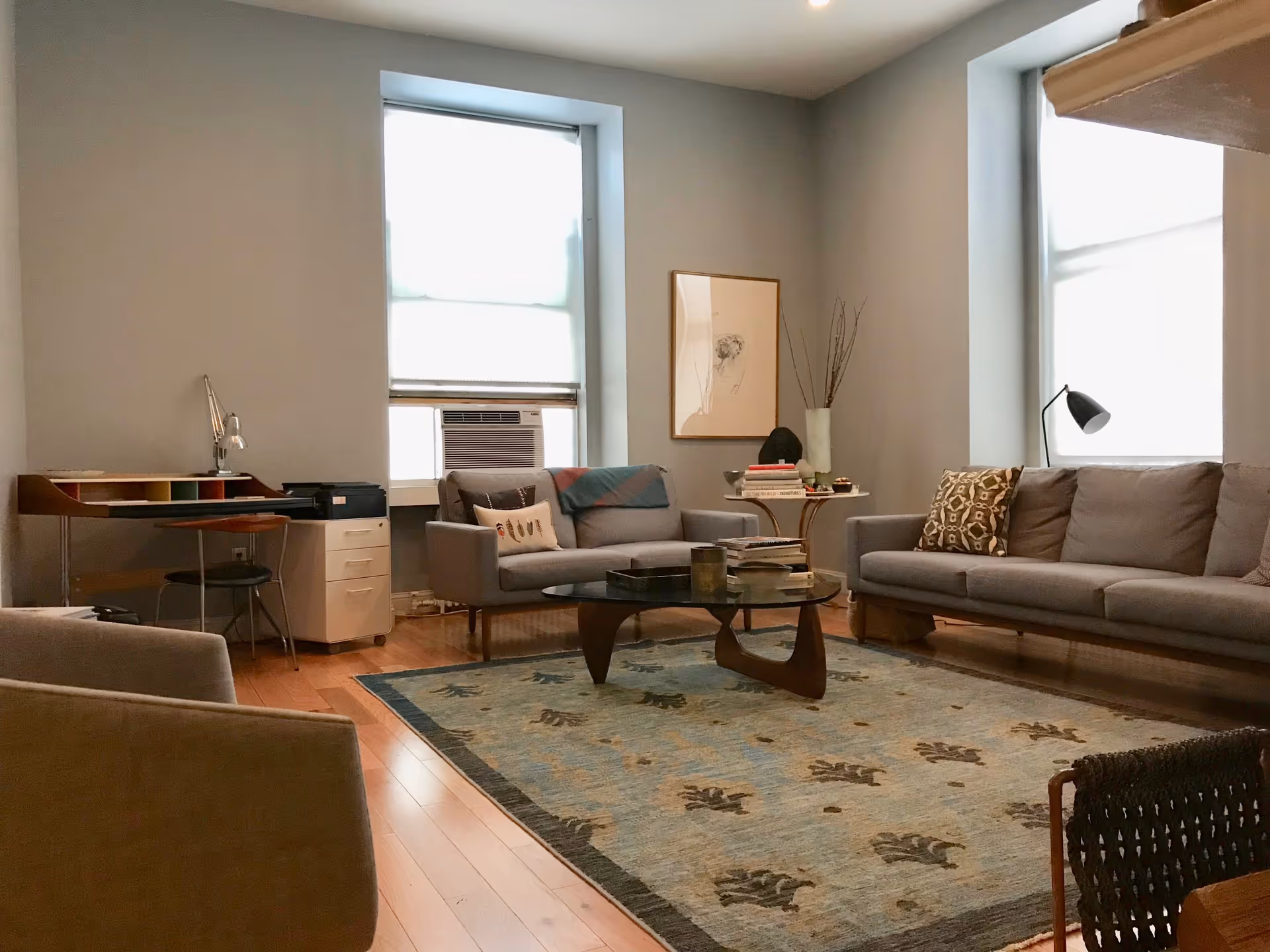 Cozy senior living lounge with sofas, a coffee table, rug, and large windows.