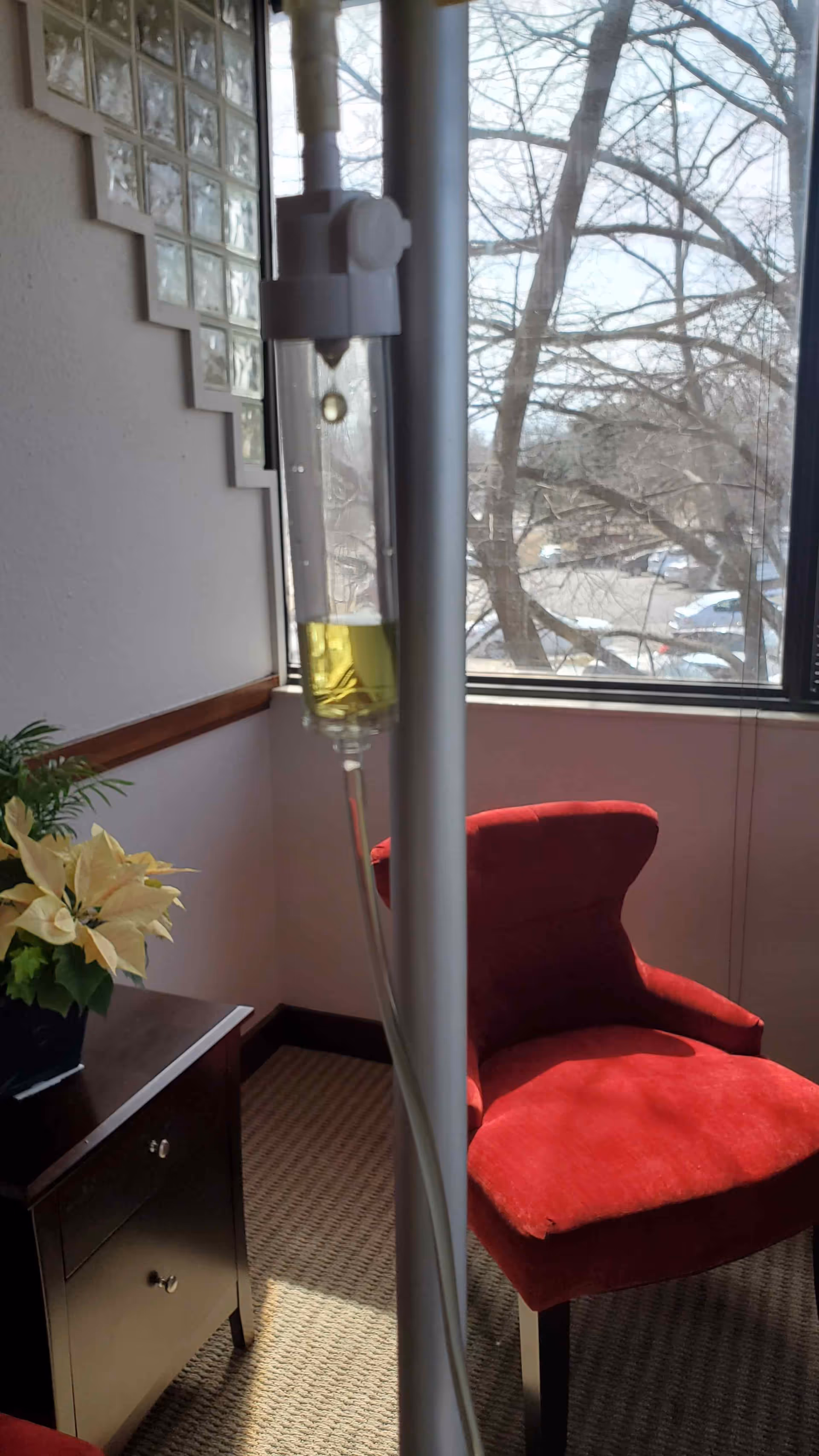 IV drip setup beside a red chair in a small clinic room.