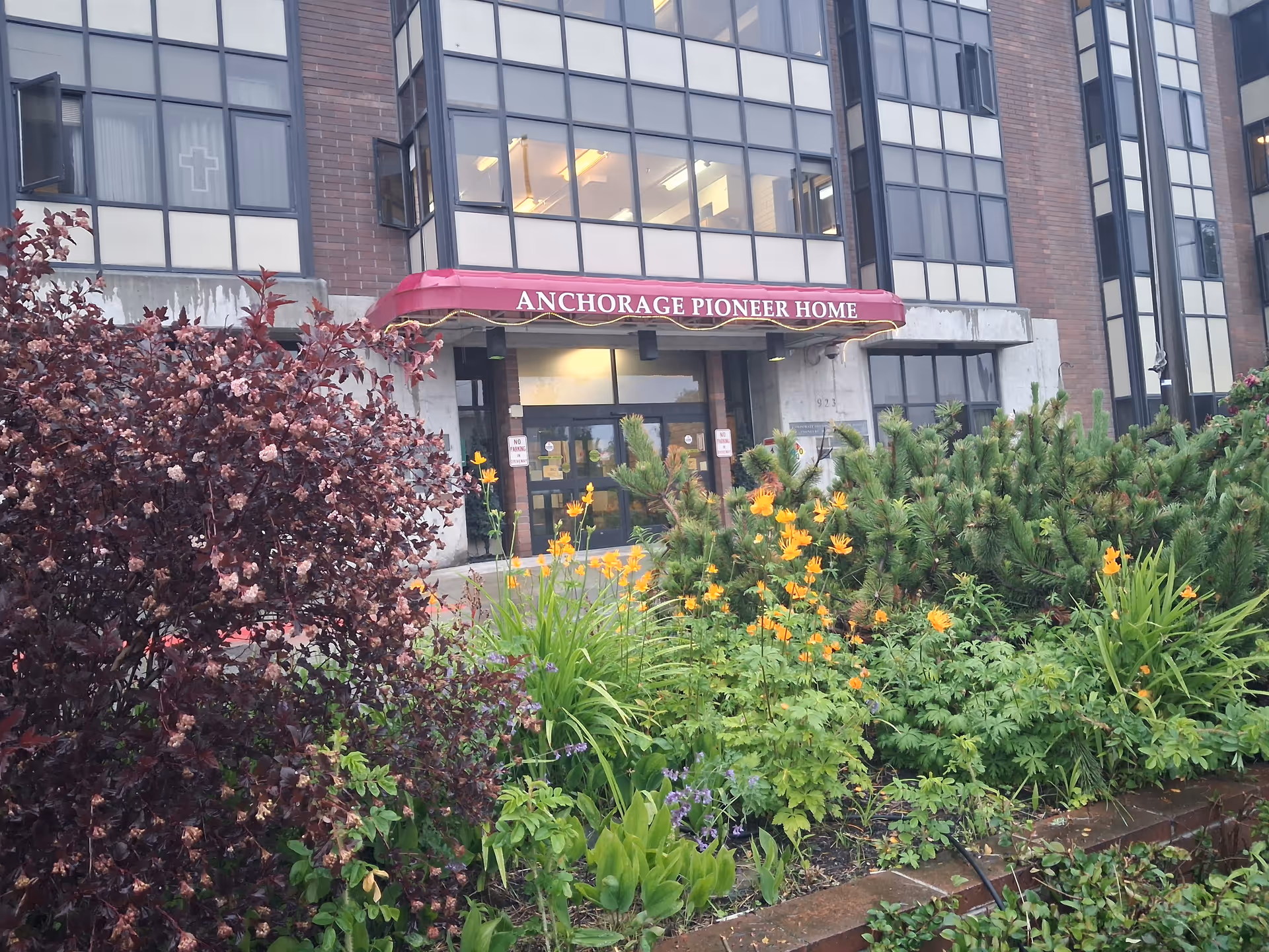 Front entrance of Anchorage Pioneer Home I with garden and colorful flowers.