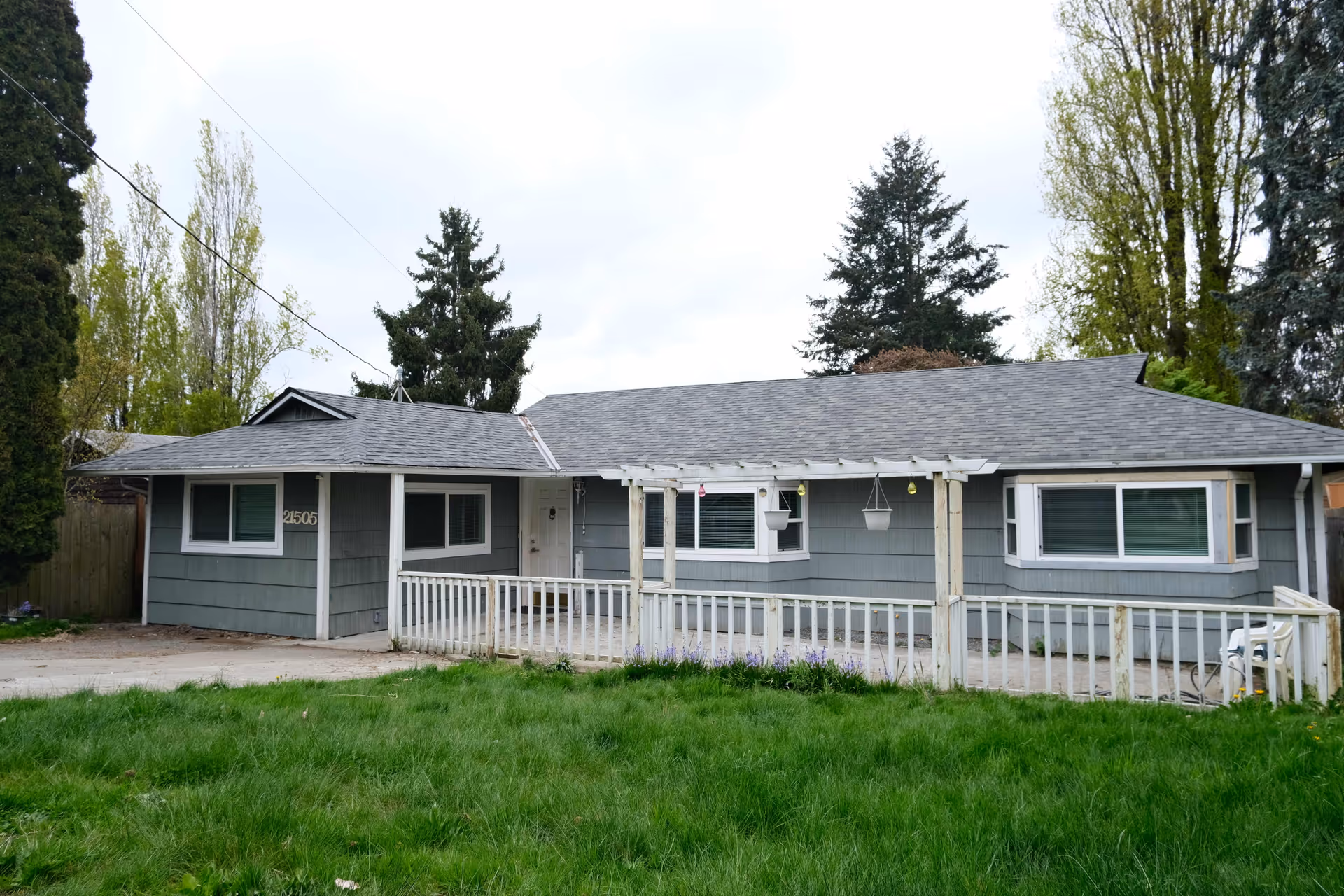 Single-story building with gray siding, white railing, and a green lawn in front.