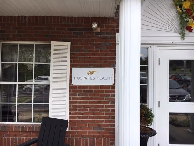 Brick facility entrance with Hosparus Health sign and glass door.