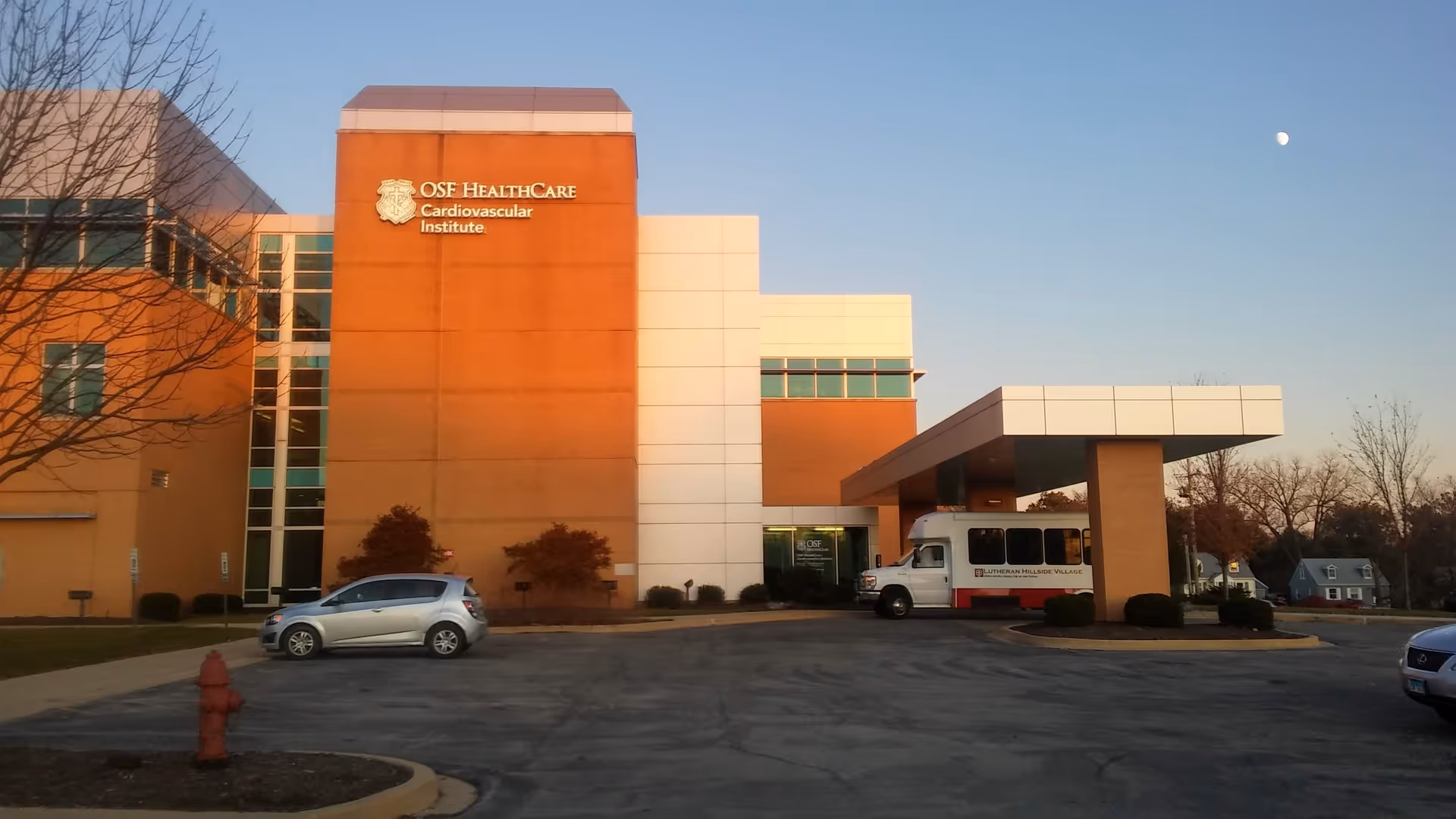 Exterior view of OSF HealthCare building with entrance canopy and vehicles.