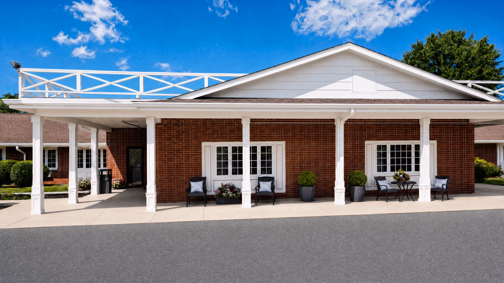 Brick facility facade with white columns and outdoor seating under a covered entrance.